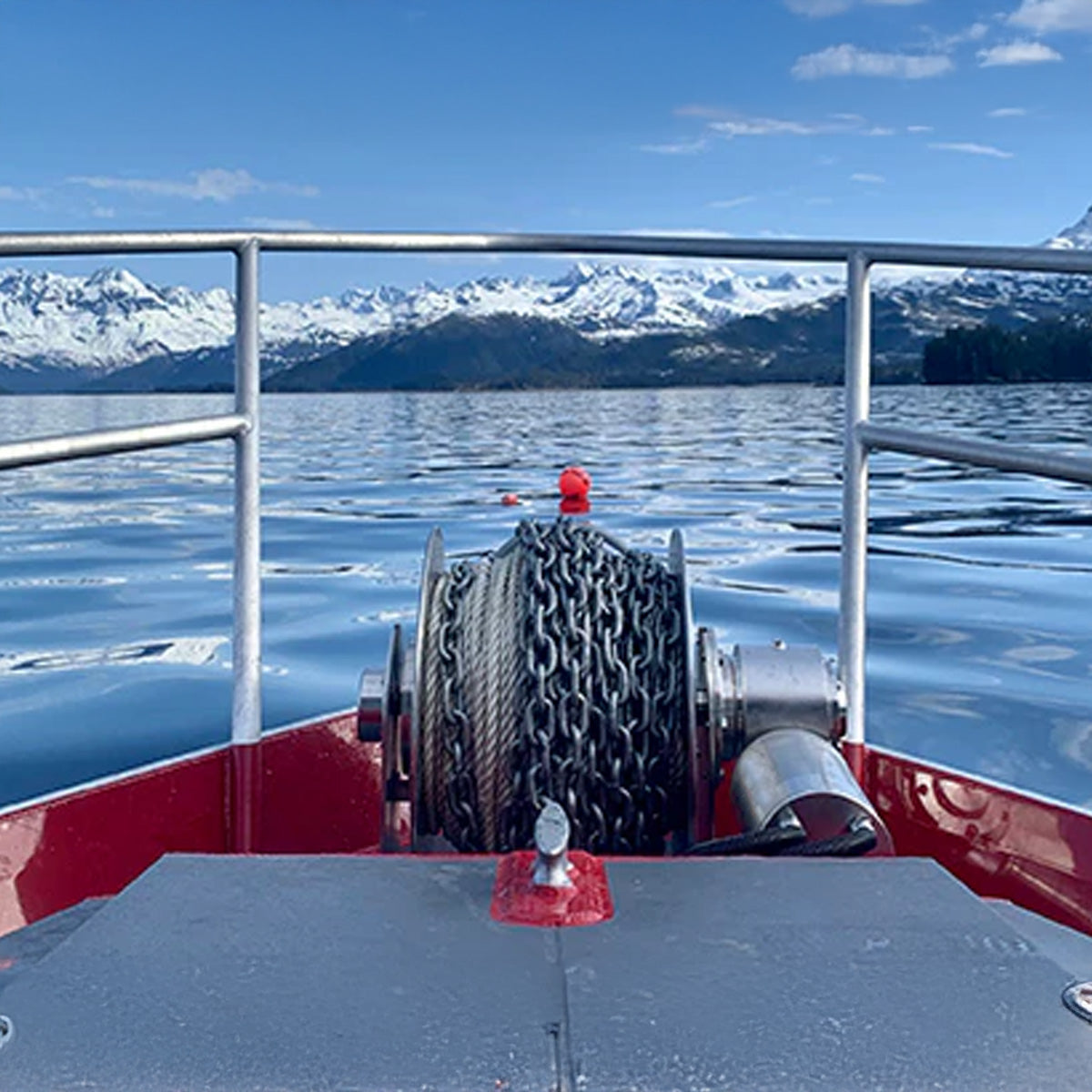 Boat with a winch on a body of water with snow-capped mountains in the background