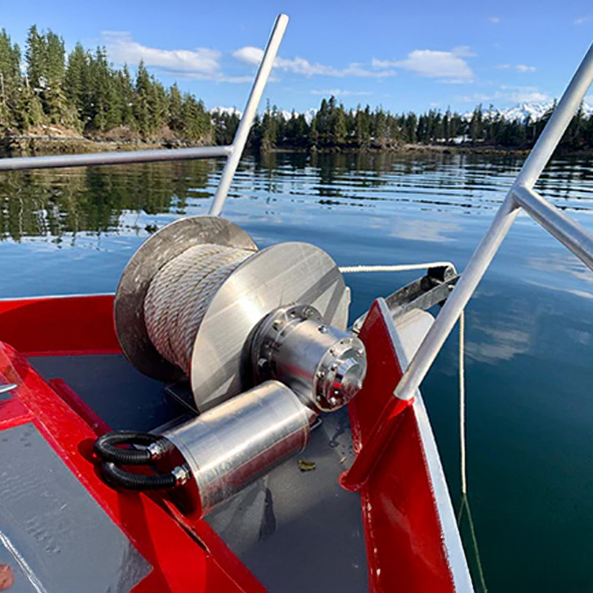 Close-up of a winch on a boat with a scenic lake and trees in the background