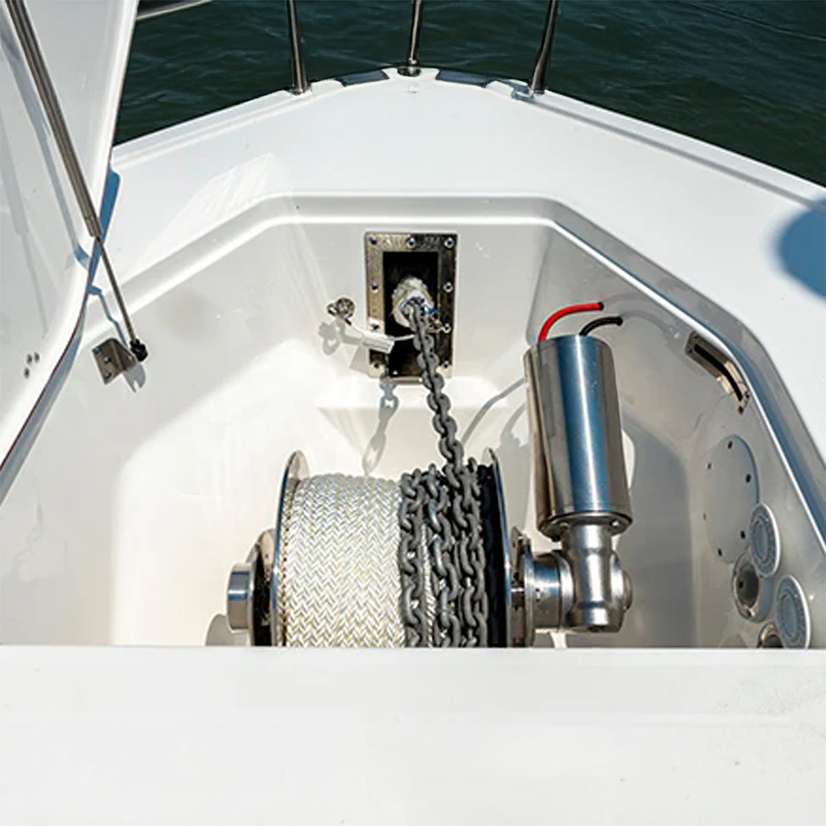 Boat winch with chain and cable on a boat deck with water in the background