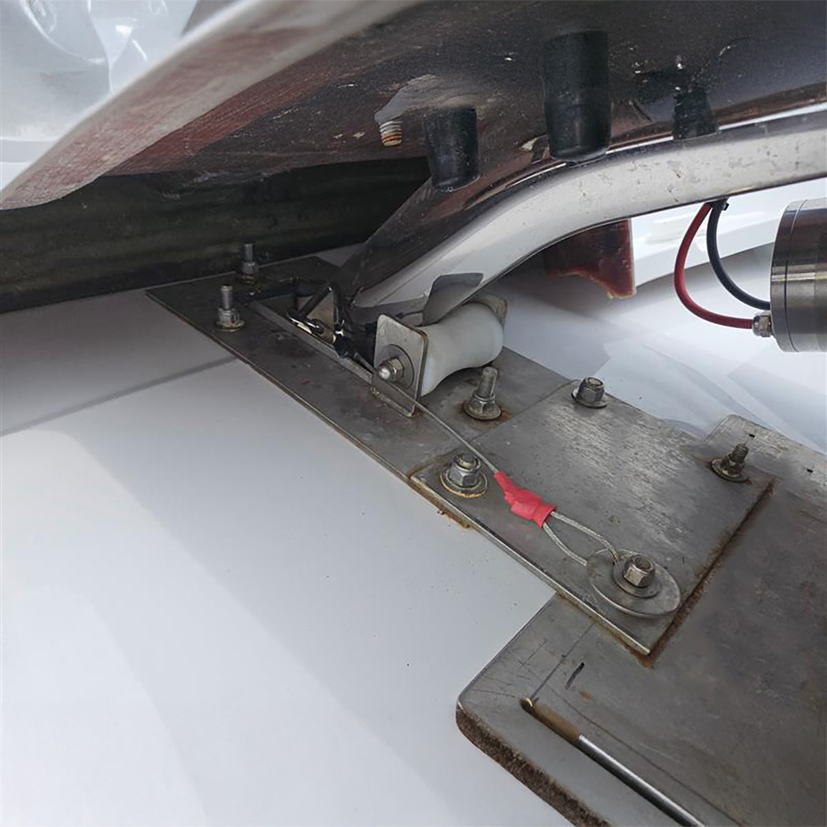 Close-up of a metal component with bolts and a red flag on a white background