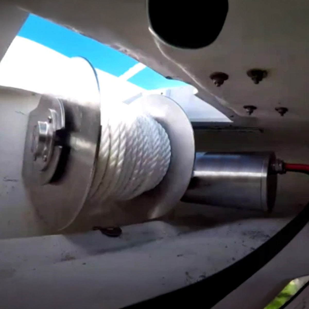 Close-up of a winch mechanism on a vehicle with a blue sky background.