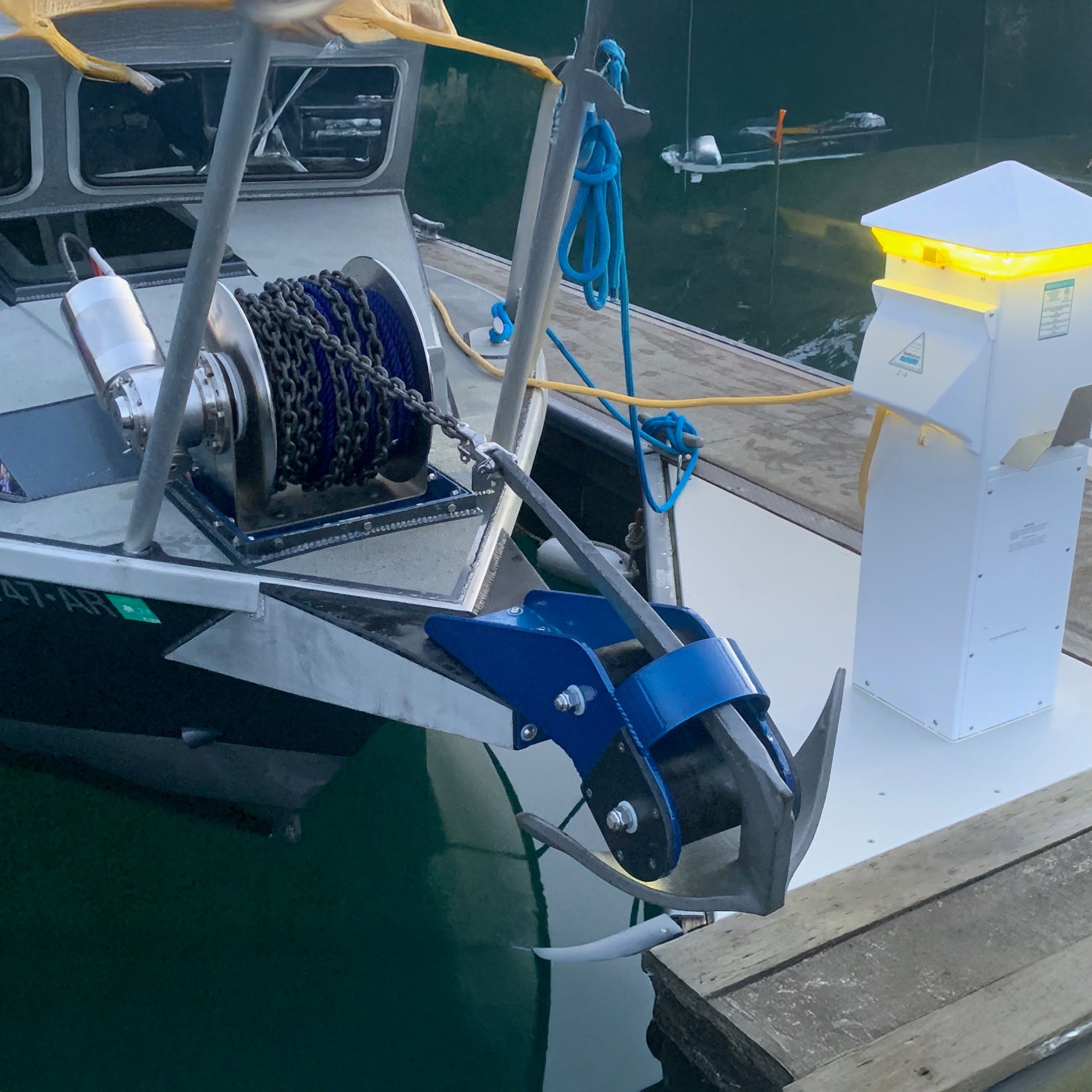 Marine anchor and winch system on a boat with water and dock in the background
