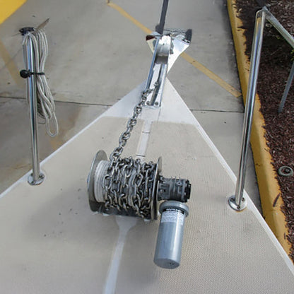 An anchor winch with a silver aluminum drum and a gray motor housing labeled 'SAILOR', featuring electrical wiring and a black handle.
